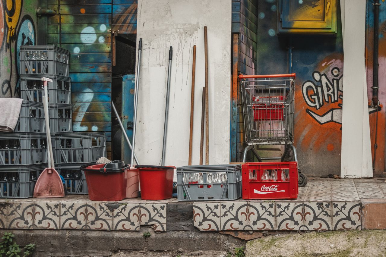 The Art of Drawing Readers In: Your attractive post title goes here A collection of cleaning supplies and crates set against an artistic, graffiti-covered wall.